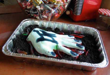 Hand of Glory on a bed of chocolate crumb dirt being crawled over by gummy worms